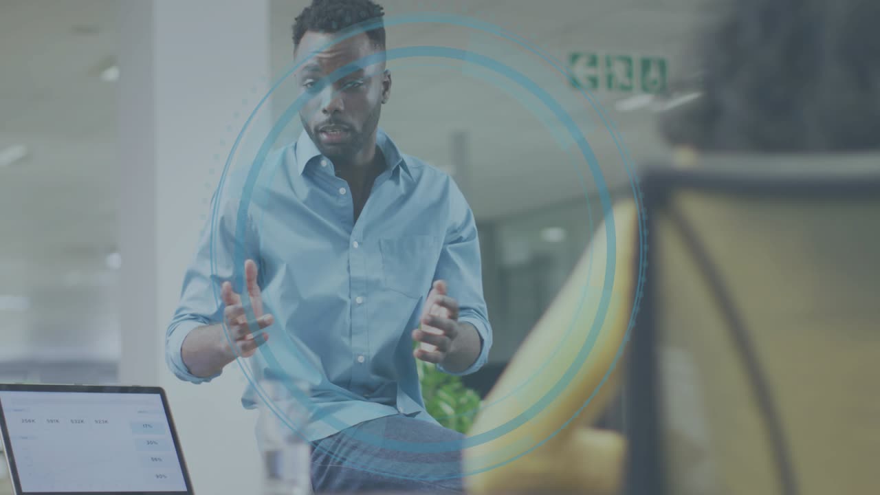 Man tapping laptop growing circle overlay around him turning and gesturing while pitching in office