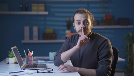 un hombre de negocios diciendo "shhh" para el silencio.