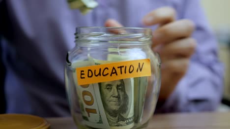 caucasian man putting a glass jar put in a drawer table with his savings for future education