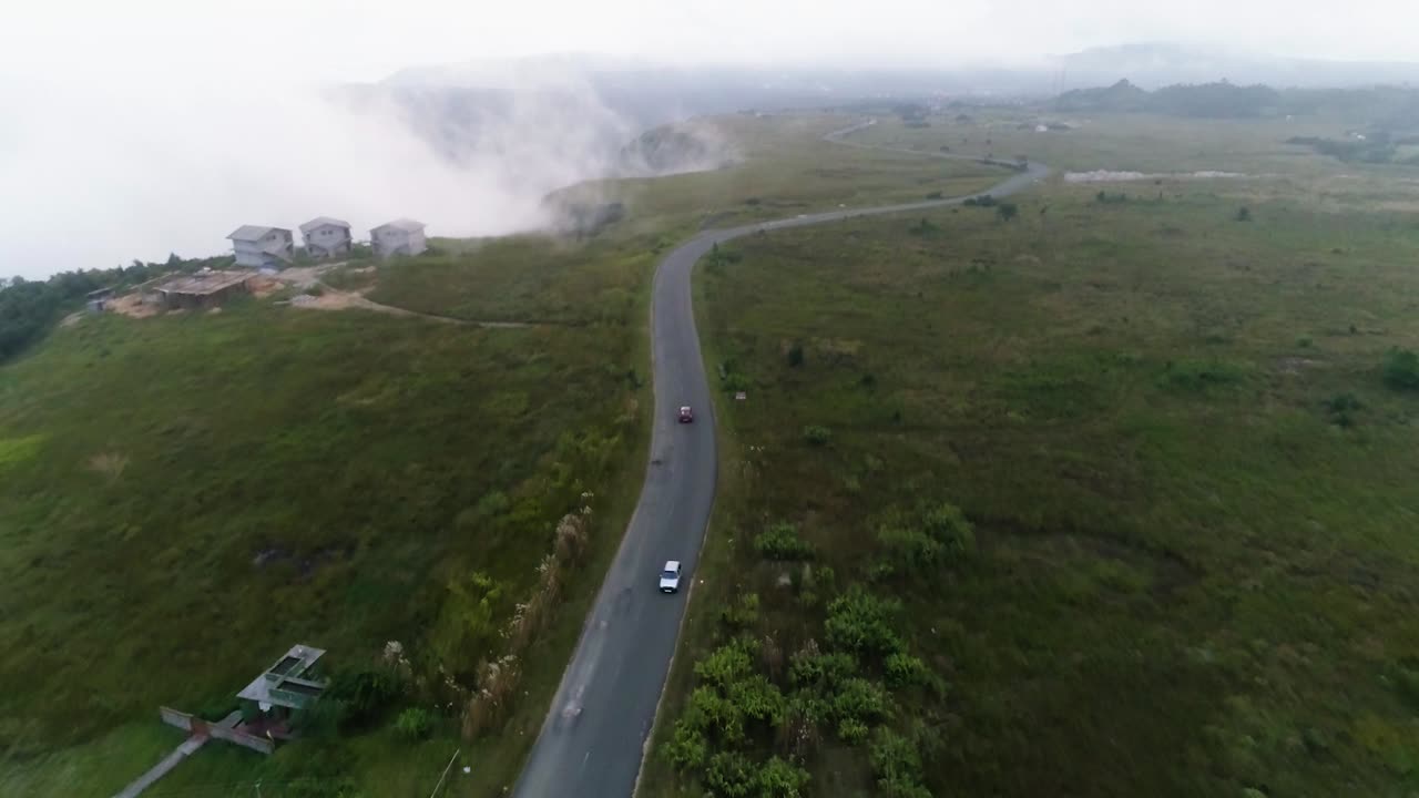 Aerial View of Winding Road Through Foggy Mountain Landscape