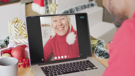 animación de un hombre afroamericano en el sombrero de santa en una llamada de video portátil con una mujer en navidad