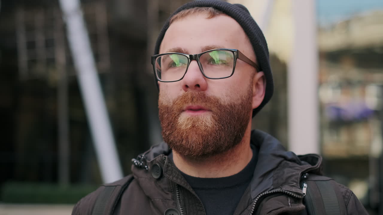 Close-up portrait of a bearded man with glasses and a beanie
