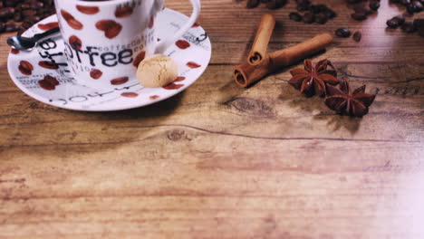 pack shot - camera moving up and revealing a freshly poured espresso cup with cinnamon, star anise and freshly roasted coffee beans on a wooden table