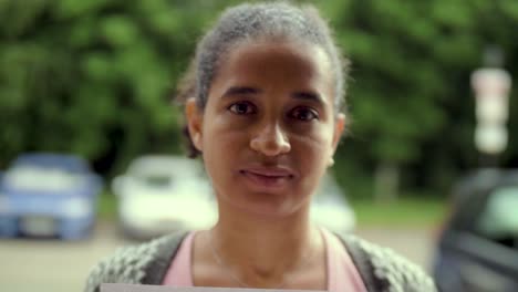 una mujer negra atractiva sostiene un cartel de protesta "detengan el racismo" frente a su cara