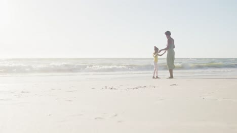 Happy-african-american-mother-and-daughter-dancing-at-beach,-in-slow-motion,-with-copy-space