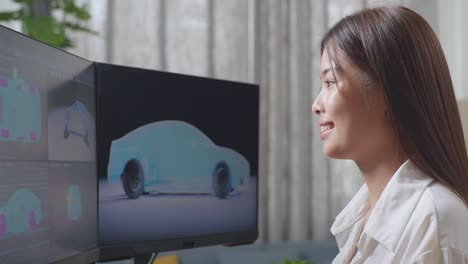 아시아 여성 자동차 디자이너가 스튜디오에서 데스크 컴퓨터에서 ev 자동차의 3d 모델을 작업하는 동안 성공을 축하하는 목표를 외치고 있습니다.