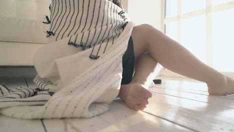 긴 다리와 플레이드가 있는 클로즈업 소녀가 나무 바닥에 앉아 있습니다.