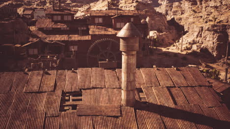 historic mining town with rusted buildings and a tall chimney in daylight