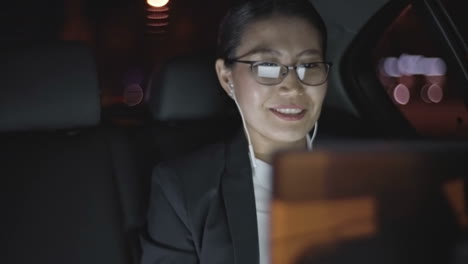 businesswoman dressed in stylish clothes sitting in moving car while making video call