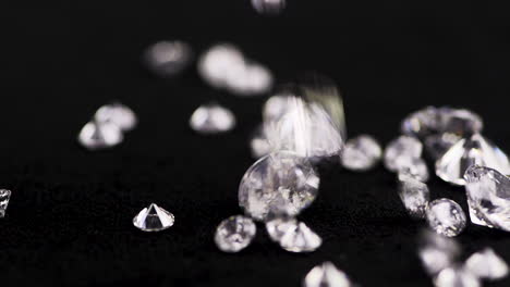 slow-motion shot of real diamonds of various sizes falling down the black table for examination in a jewelry store