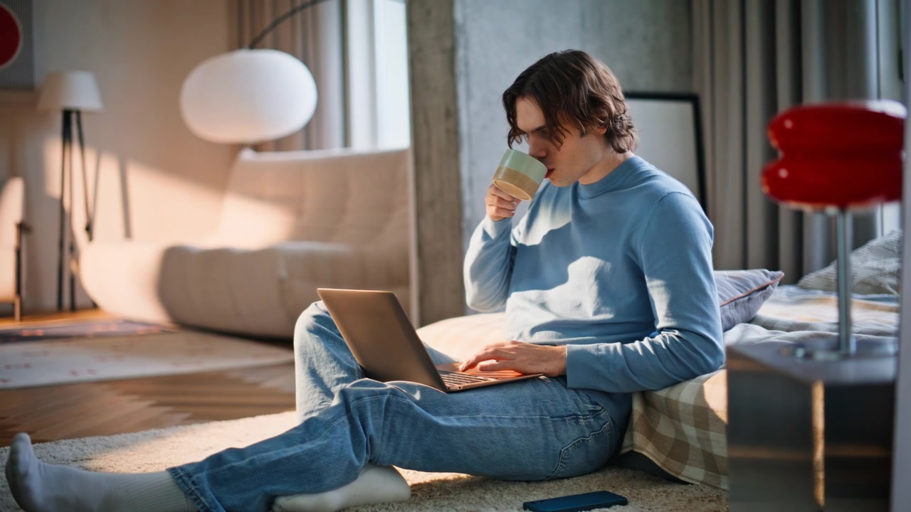 Studente da casa che scrive al portatile lavorando al chiuso. Freelance calmo che naviga al computer