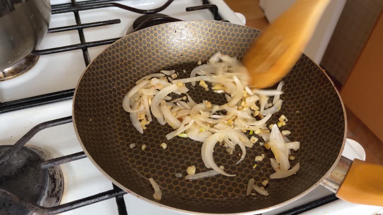 Julienne onion is sauteed and stirred with a wooden spoon, home cooking