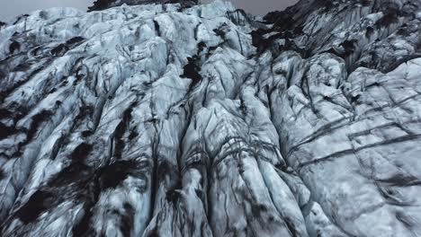 jagged ice flowing down mountain as glacier, sólheimajökull, aerial