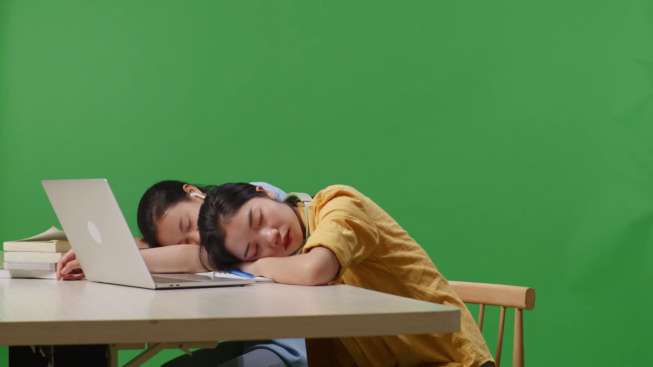 Asian Woman Students Sleeping On A Table With A Laptop While Studying In The Green Screen Background Classroom