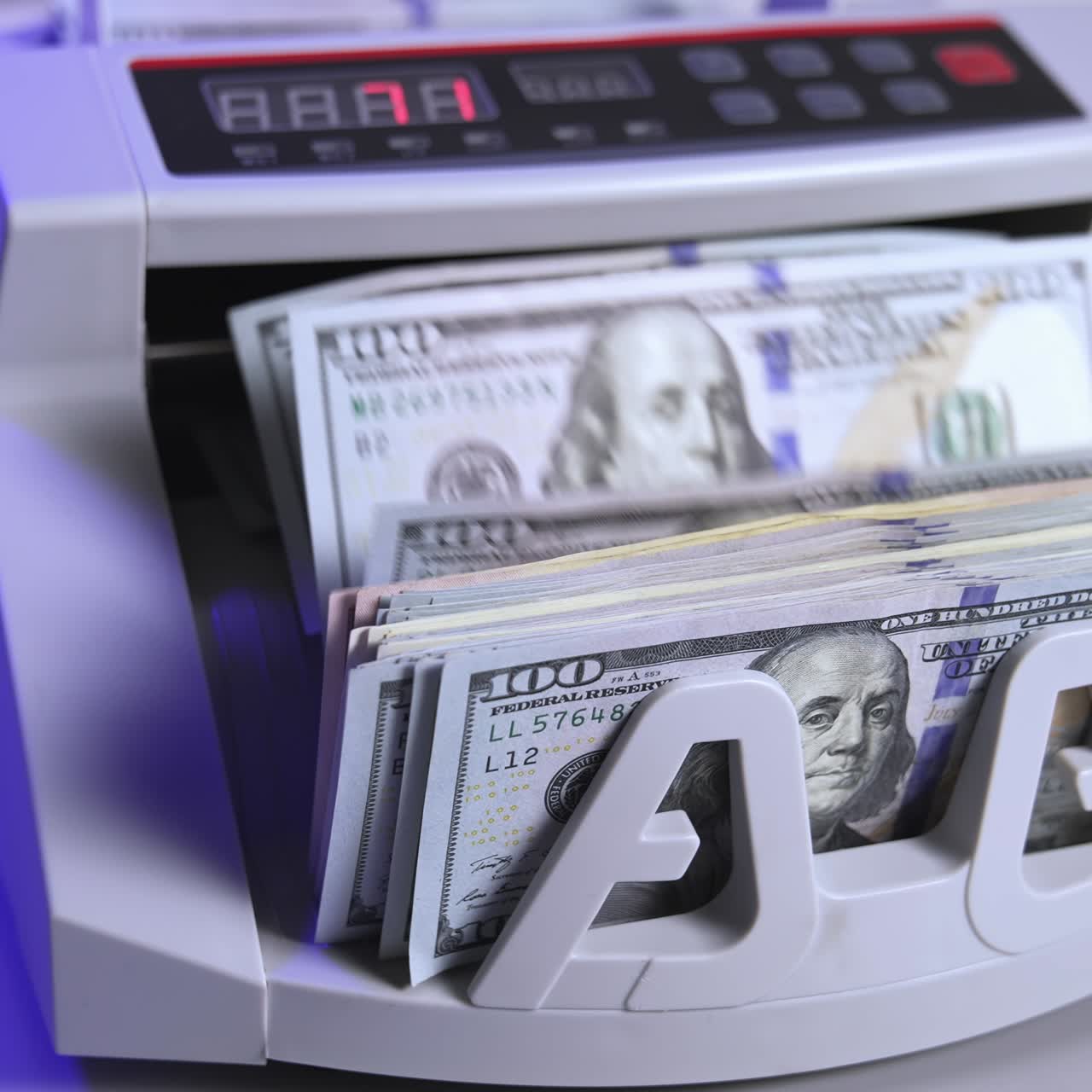 a cash count machine counts US 100 dollar bills