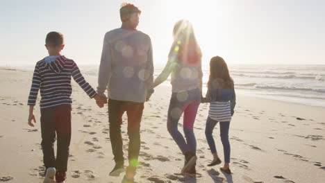 Vista-Trasera-De-La-Familia-Caminando-En-La-Playa-De-Invierno-Tomados-De-La-Mano