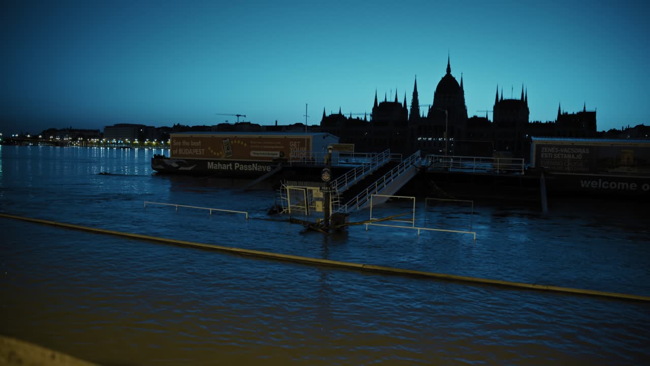 Flooded dock area in Budapest at night, with city lights reflecting on the river