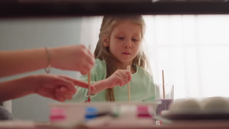 concentrated little girl with mother draws marbling patterns