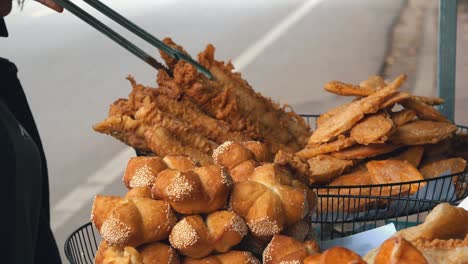 street food vendor arranging fried snacks with tongs by the side of the road