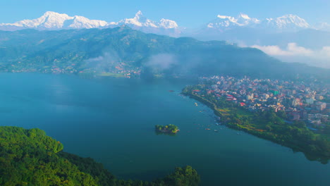 drone shot captures the stunning pokhara valley gliding through a lush green forest, revealing the pristine phewa lake and the majestic macchapuchhre and annapurna mountain ranges