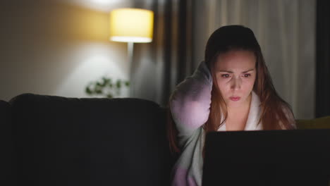 Anxious-Woman-Sitting-On-Sofa-At-Home-At-Night-Looking-At-Laptop-Concerned-About-Social-Media-Or-Bad-News-10