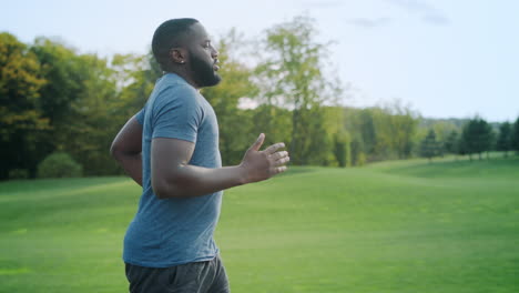 Athletic-afro-man-running-in-park.-Male-runner-training-on-asphalt-surface