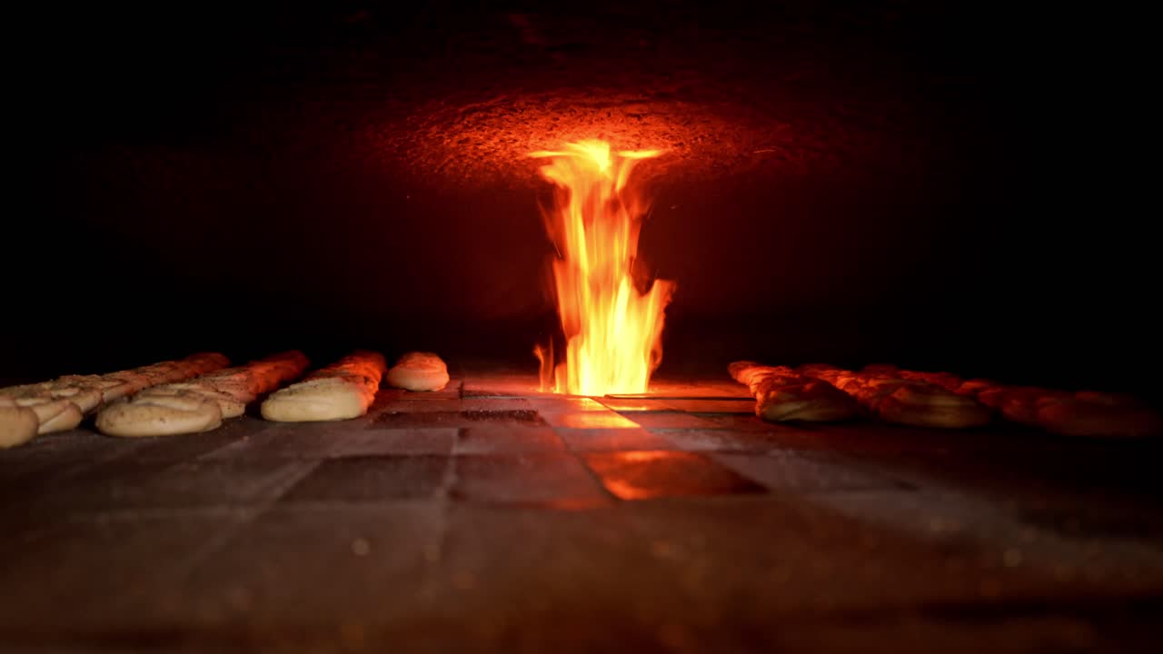 Close-up interior of a wood-fired stone oven with open flame and bread dough