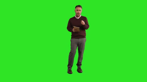 full length studio portrait of mature male teacher with notebook talking to class standing against green screen 2