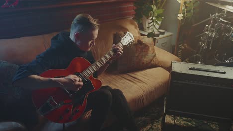 Man Playing Red Guitar on a Couch
