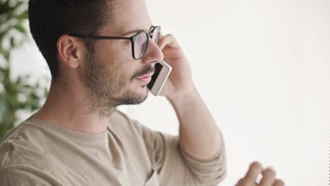hombre de negocios cansado hablando por teléfono móvil en la oficina de casa