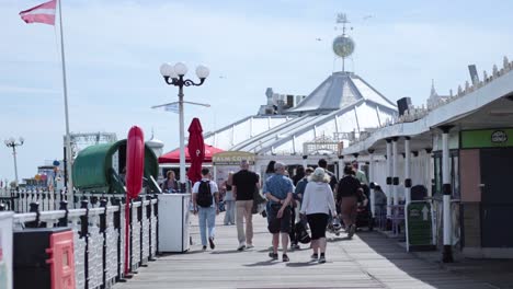 people strolling along brighton pier in summer