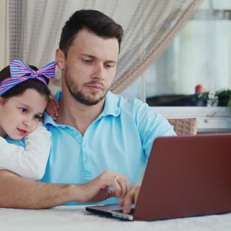 daughter watches father use laptop