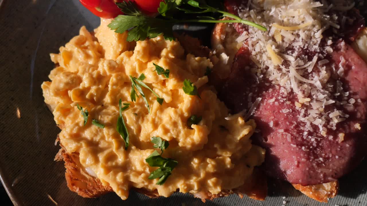Piatto da colazione con deliziose uova strapazzate e carne affettata