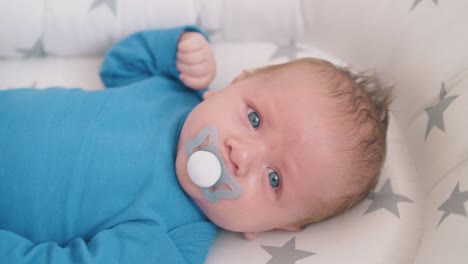 un niño triste con un chupete se encuentra durmiendo en un capullo en primer plano