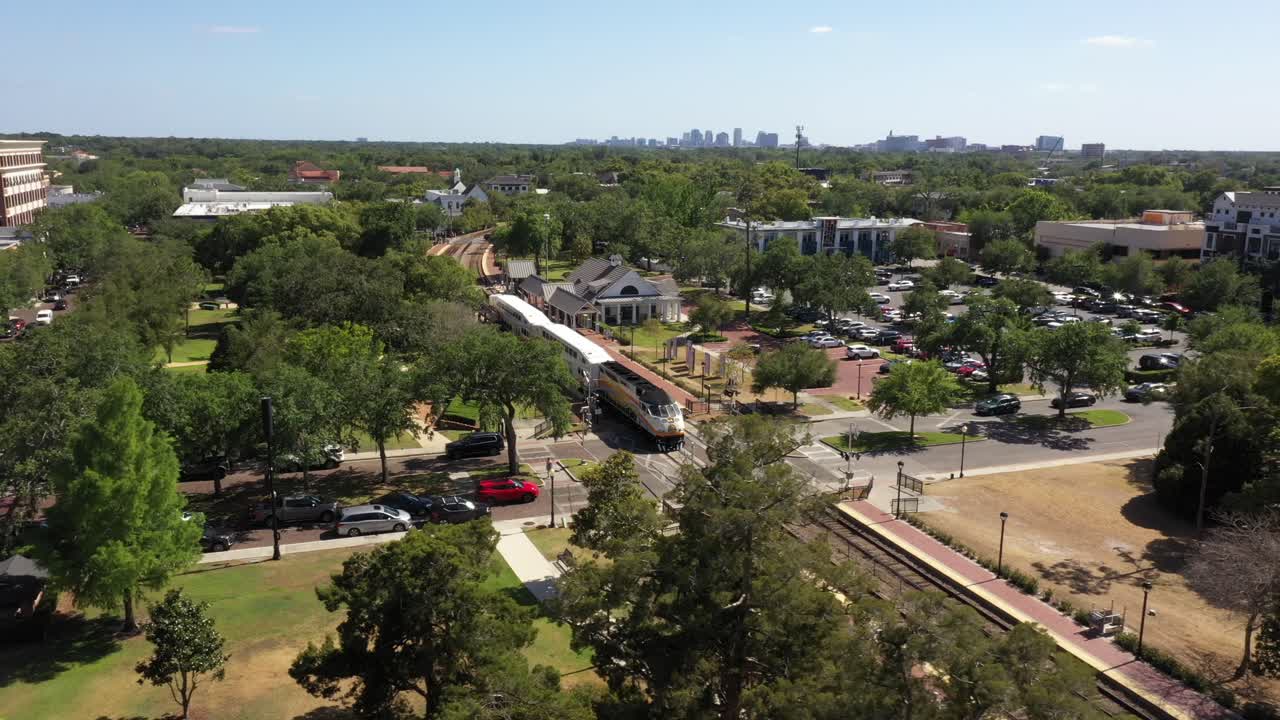 Aerial estabilshing reveal of downtown Winter Park showing roads, trees, and buildings under sunlight