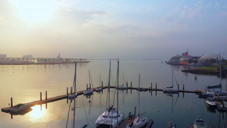 Sailboats-docked-at-the-harbor-at-Long-Beach,-California---sliding-aerial-view-at-sunset