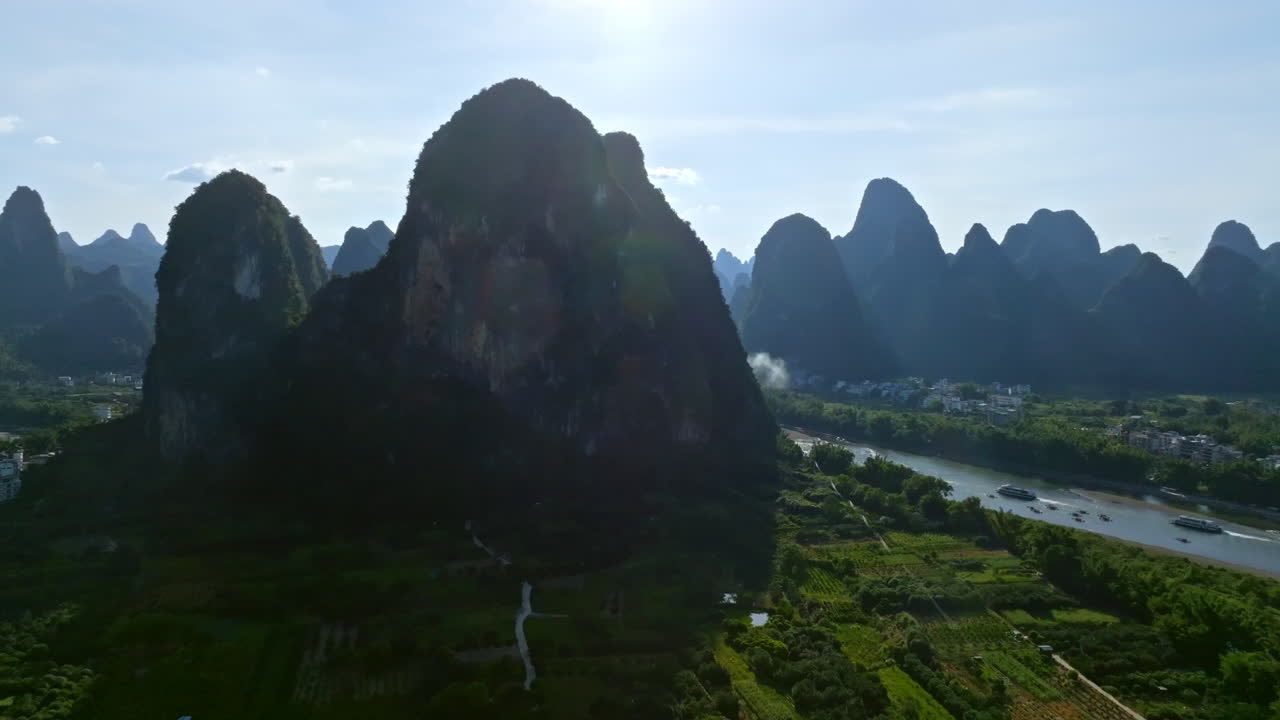 Aerial tracking shot of karst peaks and riverboats, summer day in Xingping, China