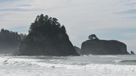 aerial shot of rugged sea stacks off the pacific northwest coast surrounded by ocean waves and mist