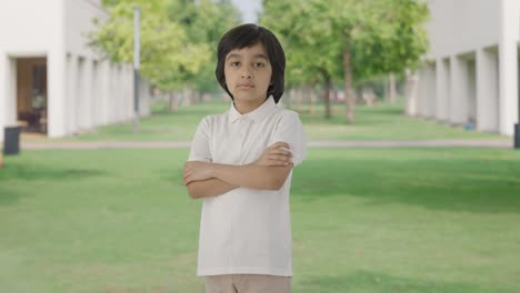 portrait of confident indian boy standing crossed hands in park