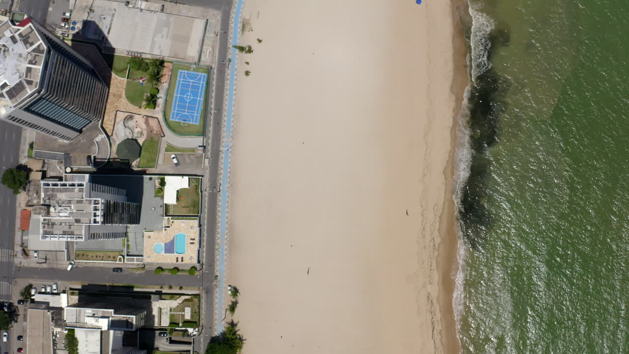 High angle shot of Jaboatão dos Guararapes beachfront Pernambuco Brazil with its distinctive sea white sand clear blue sky coastal buildings perfect for summer holidays featuring a boat and sunshade.