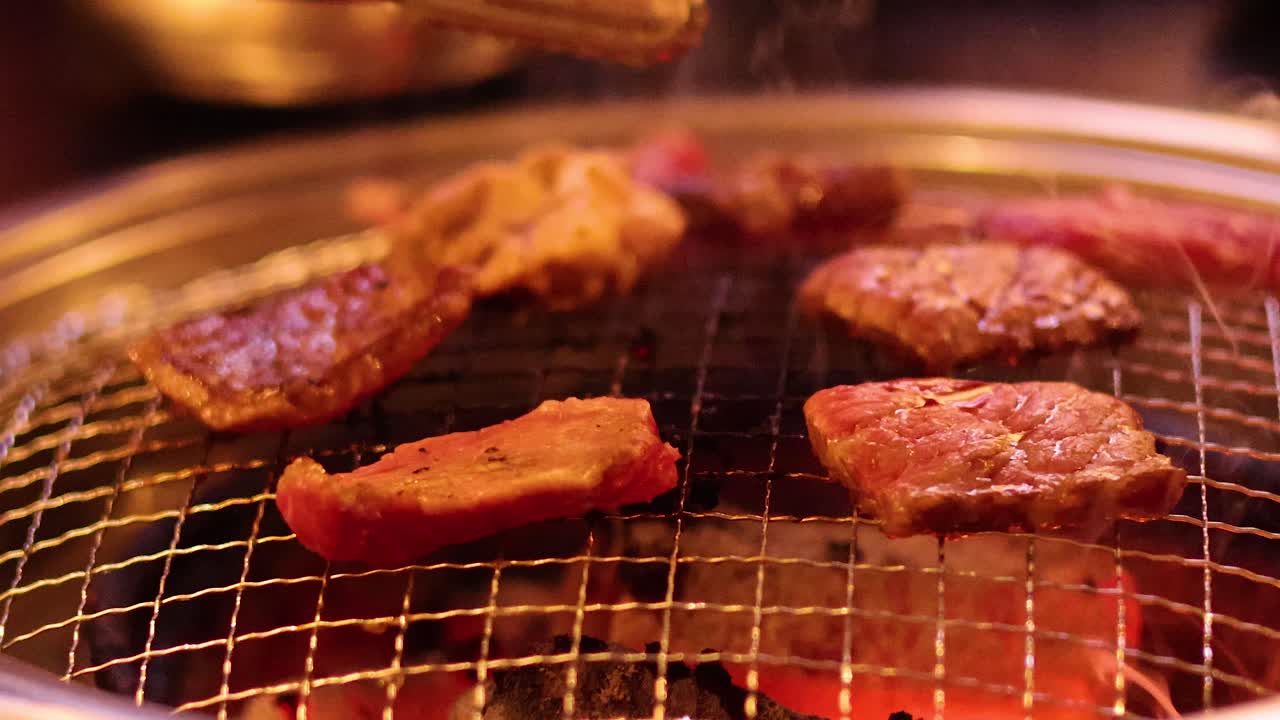 Meat grilling on barbecue with tongs