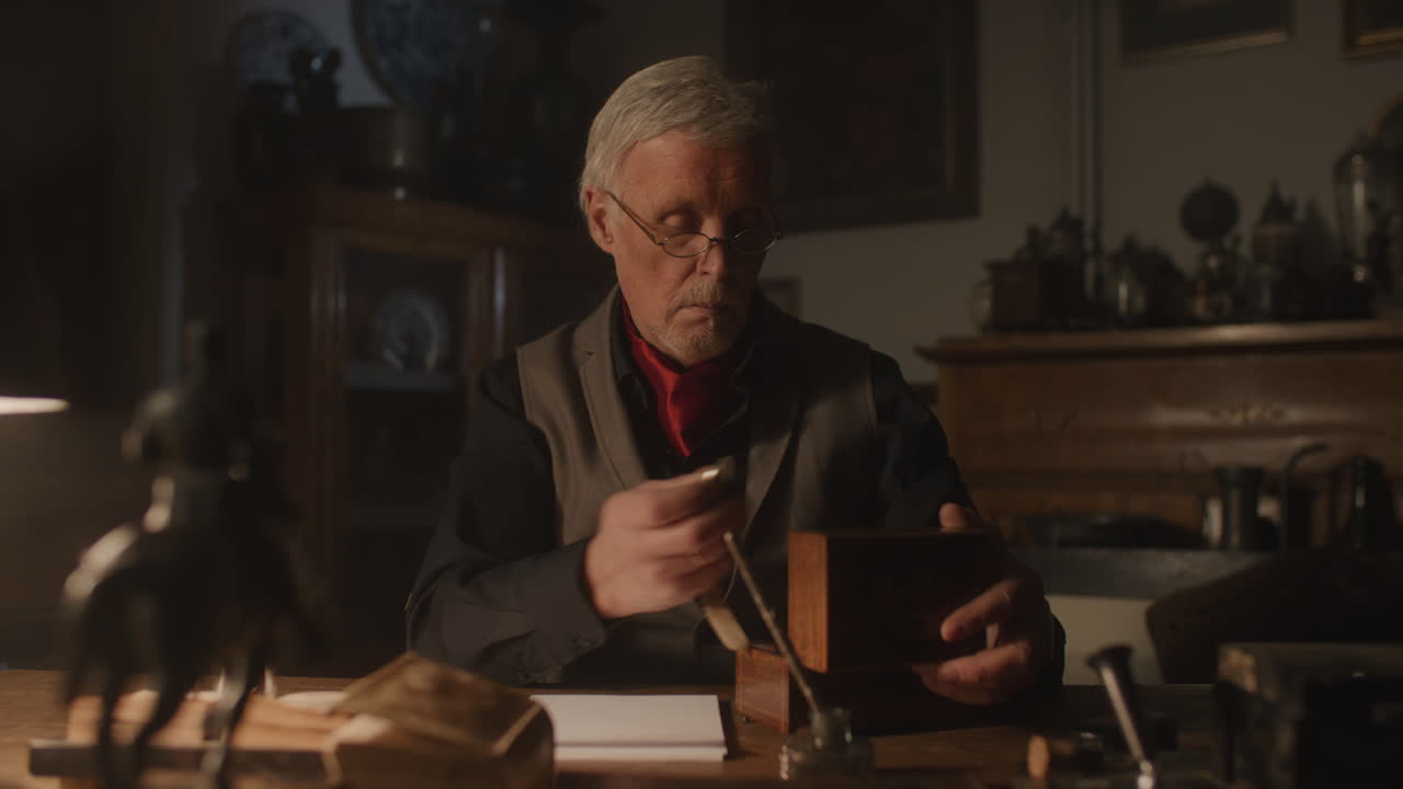 Older passionate man evaluates an old watch in his office at night