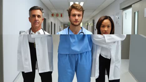 portrait of doctors standing with arms crossed in corridor