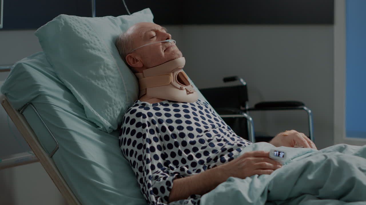 Old patient sitting in hospital ward bed with neck collar