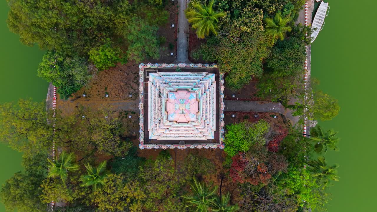 Vista aerea dall'alto di un santuario templare centrato su un'isola quadrata all'interno di acqua verde, circondato da alberi fitti, una volta di palme e sentieri che creano un suggestivo motivo geometrico in un bacino storico.