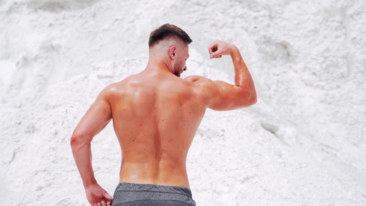 Athletic man demonstrates his trained strong muscles. Professional bodybuilding