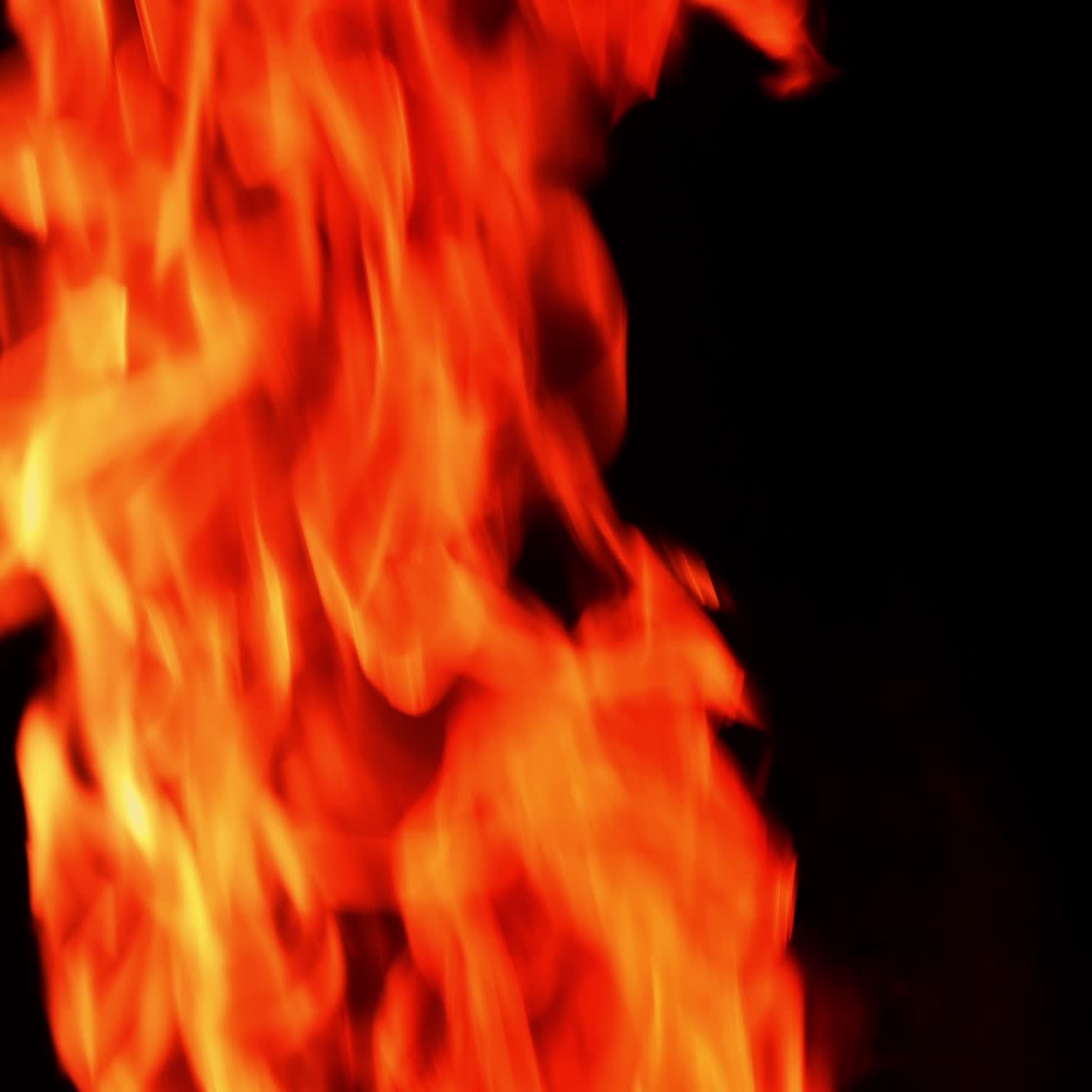 Brændende lejrbål mod en helt sort baggrund. Små orange flammer, der hurtigt stiger op.