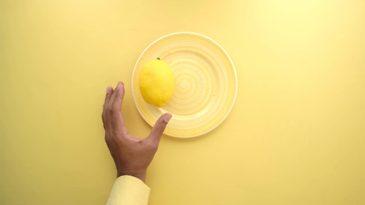 Mano sosteniendo limones en un plato amarillo