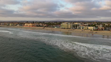 Imperial-Beach-Mit-Surfern-Im-Ozean-Und-Menschen,-Die-Sich-An-Der-Küste-Entspannen,-Mit-Gebäuden-Am-Wasser-Im-Hintergrund