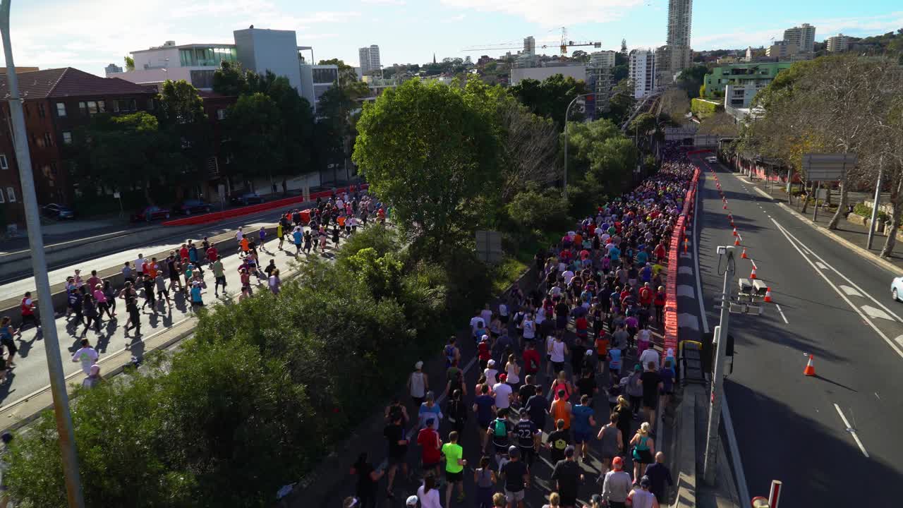 People participating in a running contest. They are running on the two streets that are closed for the cars.
